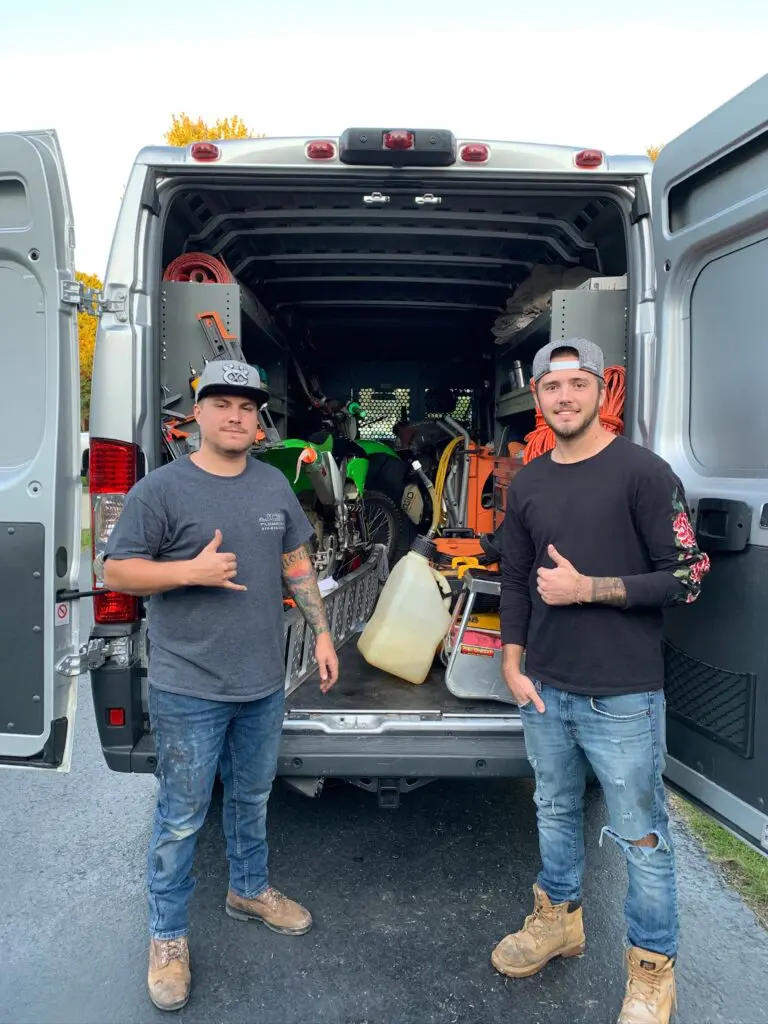 Austin and his business partner are standing behind their company truck, which they use for their trade-based business 